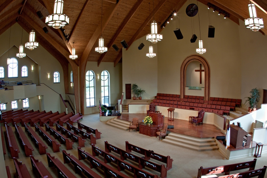 A baptism moment inside a church sanctuary, with a minister gently lowering a person into a baptismal pool while congregants watch quietly