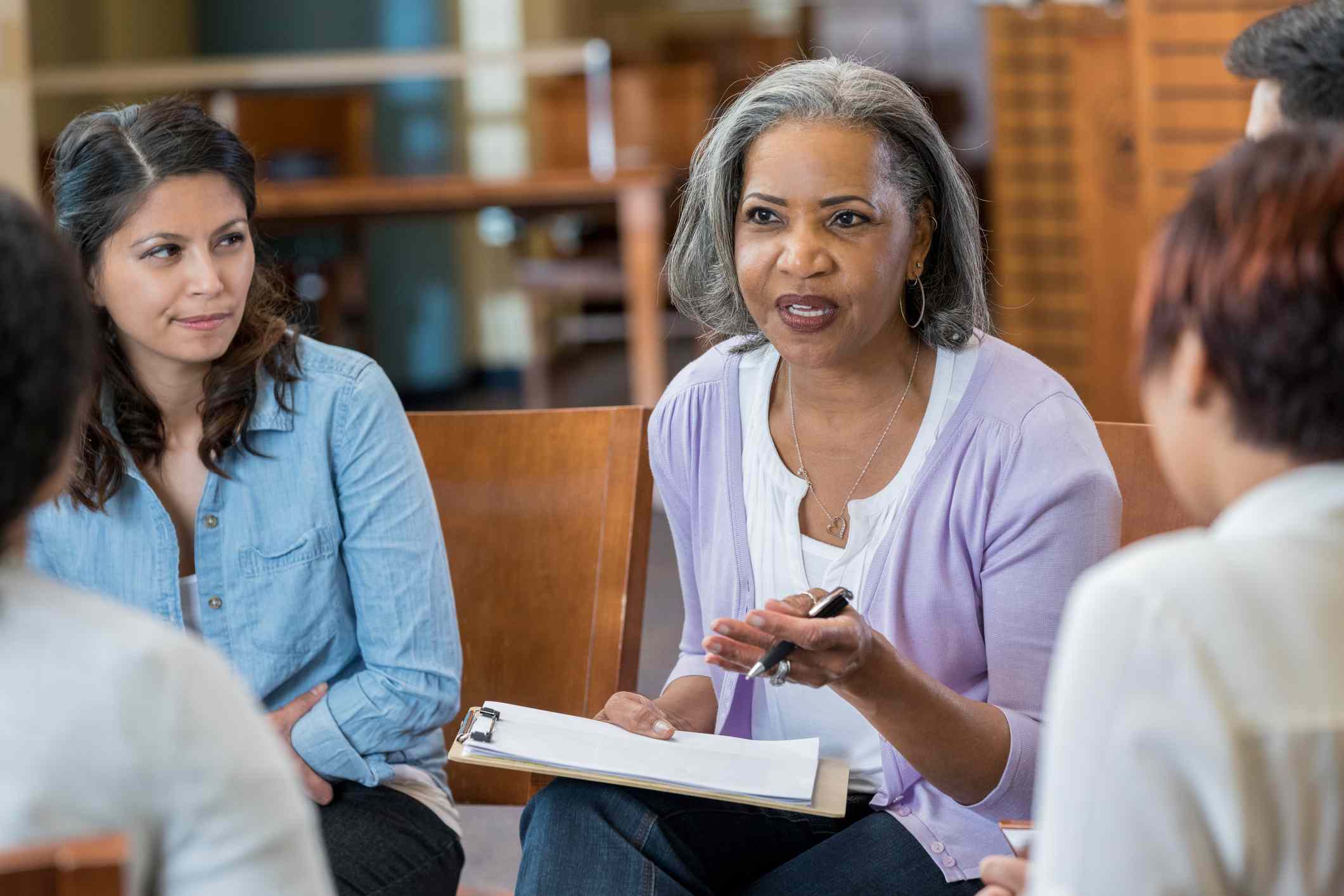 A person sitting in a comfortable therapist office speaking with a counselor across a small table, warm natural light coming through a window