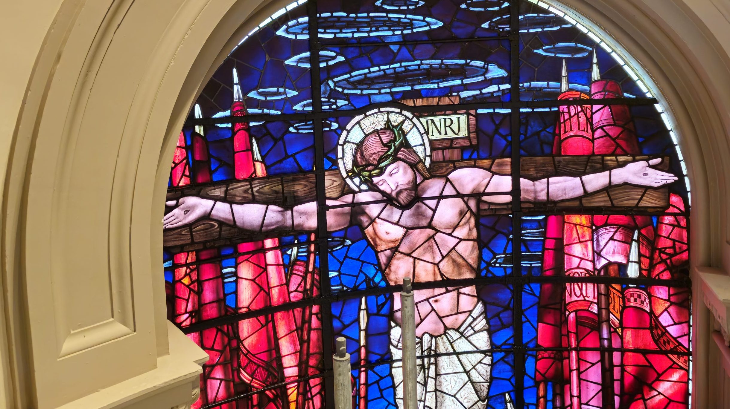 A quiet church interior with stained glass depicting Jesus on the cross, soft morning light streaming through the windows