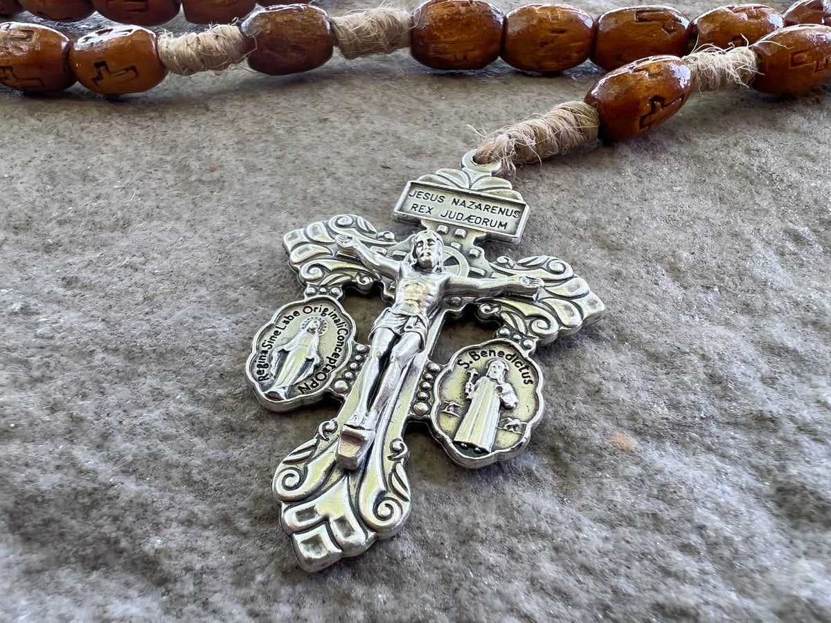 A rosary crucifix resting against the beads on a wooden table in warm light